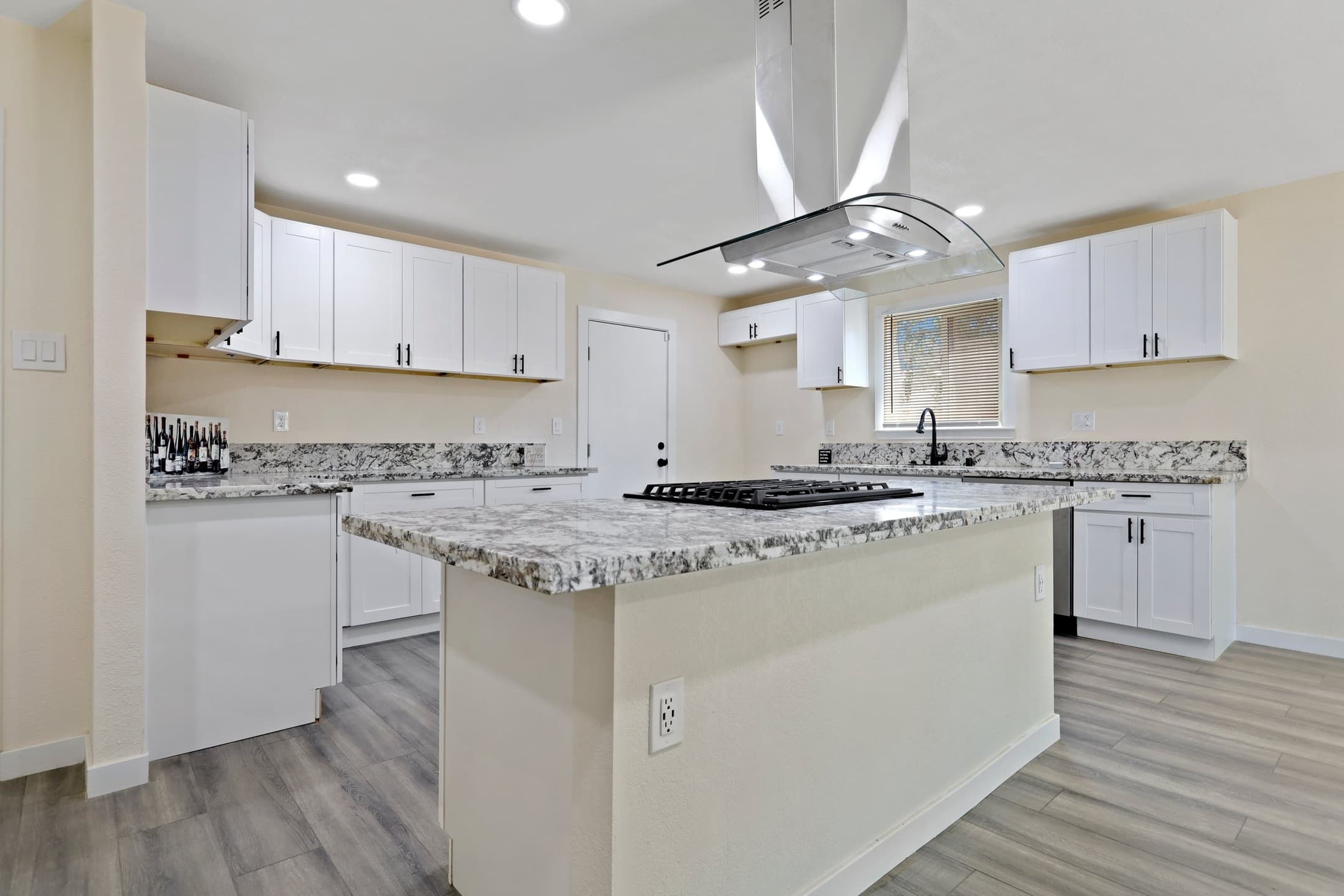 Completed kitchen renovation after cash purchase - white shaker cabinets, granite island with cooktop